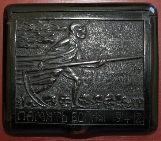 Wooden cigarette box carved by Г. САВИНСКИ (?; G. Savinskiy), a Russian POW. The Grim Reaper strides across a field of skulls on the cover. The base includes an intricate carving of the years of war years, '1914' and, turning it 90 degrees, '1918.'
Text:
ПДМЯТЬ ВОИНЬ 1914-18
To memory of soldiers 1914-18
Reverse:
1914
1918
Г. САВИНСКИ (?)
G. Savinskaya