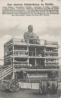 The massive Iron Hindenburg in Berlin, its decorative scaffolding and cannons. One method to raise war funds was through nailings, charging for adding a nail to a wooden iron cross, statue or other object. Berlin was the site of this massive statue of General Paul von Hindenburg, hero of the Battle of Tannenberg. One could nail an iron, silver, or gold nail for 1, 5, or 100 marks respectively.
Text:
Der eiserne Hindenburg zu Berlin
Höhe: 13 Mtr. - Kopfhöhe: 1,35 Mtr. - Durchm.: 3,14 Mtr. - Größter Umfang: 9 Mtr. - Gewicht: 20000 Kg. Erlenholz und 7000 Kg. Eisen für die innere Konstruktion. - Zur Benagelung sind 6000 Kg. goldene, silberne u. eiserne Nägel bereitgestellt, zum Preise von 100, 5 u. 1 M. Man beachte unsere Feldgrauen bei der Nagelung, sie erscheinen wie übermütige Jungen im Arm des Vaters.

The Iron Hindenburg in Berlin
Height: 13 meters - Head Height: 1.35 meters - Dia. 3.14 meters - Greatest Extent: 9 meters - Weight: 20,000 Kg., 7,000 Kg. alder wood and iron for the inner construction. - 6,000 Kg. of gold, silver and iron nails are available for nailing, at the price of 100, 5 and 1 Mark. Note our troops in field gray who are nailing; they seem like wanton boys in their father's arm.

Reverse:
Dated and postmarked May 19, 1916 from Berlin.